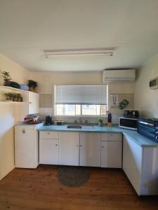 a kitchen with white cabinets and a sink and a window at Park Beach Cabins in Coffs Harbour