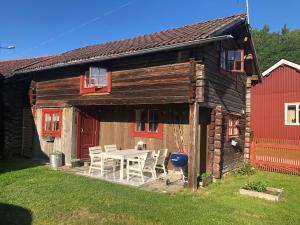 a wooden house with a table and a red barn at Stallet - Hemma hos Mait in Mora