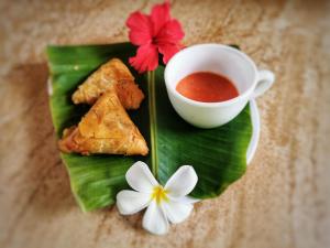 a plate of food on a banana leaf with a cup of sauce at COCO REEF ECOLODGE in Kizimkazi