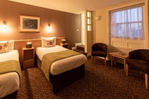 une chambre d'hôtel avec deux lits et une chaise dans l'établissement The Darlington Hyde Park, à Londres