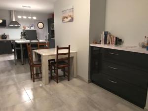 cocina con mesa, sillas y barra en Le Clos Des Pinsons, en Barneville-Carteret