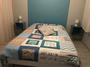 ein Bett mit einer Decke in einem Schlafzimmer in der Unterkunft Le Clos Des Pinsons in Barneville-Carteret