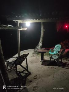 two chairs and a picnic table in a patio at night at Eddie`s Beach Resort Siargao in General Luna