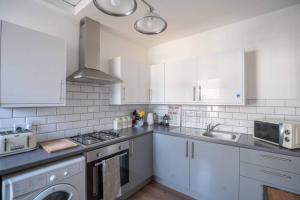 a kitchen with white cabinets and a stove top oven at Phenix Central - Huge 3 Bed, Super Equipped Apartment. in Cardiff