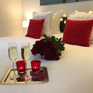 a bed with two glasses of wine and a tray of roses at Leopold5 Luxe-Design Apartment in Ostend