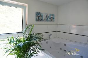Baño blanco con bañera con planta en FeWo Seeglanz, en Rieden