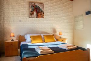 a bedroom with a bed with yellow pillows and two lamps at New Okella Hotel at Saittas in Saittas