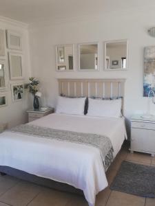 a bedroom with a large white bed with white cabinets at Claire's in Ballito