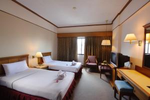 a hotel room with two beds and a television at Betong Merlin Hotel in Betong