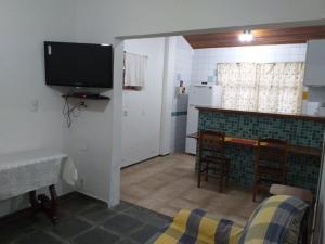 a living room with a flat screen tv and a kitchen at Casa 2 quartos in Maresias