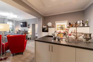 a kitchen and a living room with a red chair at Ferienwohnungen am Wintergarten in Gera