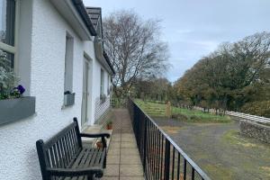 eine Bank an der Seite eines Gebäudes mit einem Zaun in der Unterkunft The Lambing Shed at Walkmill Farm in Bushmills