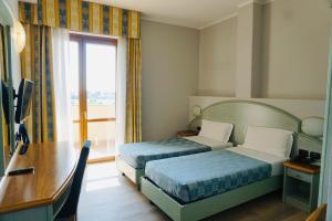 a hotel room with two beds and a desk and a window at Hotel Europa Milano in Rosate +29 photos