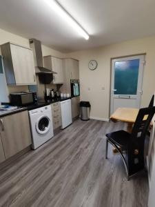 uma grande cozinha com uma mesa e uma máquina de lavar roupa em Gwynedd House Flat 3 em Pentraeth