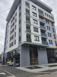 a tall white building with a parking lot at Lux OPERA 2 in Banja Luka