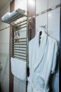 Una bata blanca colgando de un toallero en el baño. en Shine House Hotel, en Adler