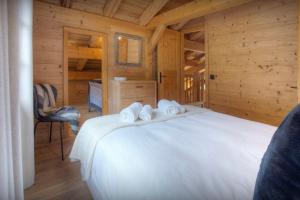 a bedroom with a white bed in a wooden cabin at Chalet Cosyneige - OVO Network in La Clusaz