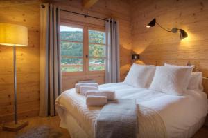 a bedroom with a large white bed with a window at Chalet Cosyneige - OVO Network in La Clusaz