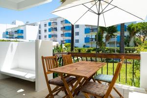 - une table et des chaises en bois sur un balcon avec un parasol dans l'établissement Serenity by Intiholidays, à Quarteira