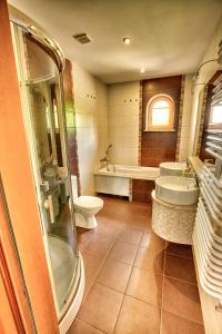 uma casa de banho com 2 lavatórios, uma banheira e um WC. em Dębowa Dziupla em Białowieża