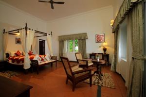 a living room with a bed and a table and chairs at Parisons Plantation Experiences by Abad in Mananthavady
