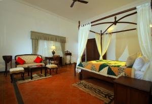 a bedroom with a bed and a chair and a table at Parisons Plantation Experiences by Abad in Mananthavady