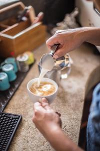 een persoon die melk in een kop koffie giet bij Un Sueño Cabañas del Pacífico in San Agustinillo