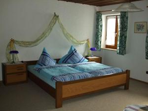 Schlafzimmer mit einem Bett mit blauer Bettwäsche und einem Fenster in der Unterkunft Weissenhof in Rottau