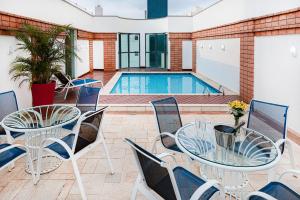 um pátio com uma mesa e cadeiras e uma piscina em Hotel Nacional Inn Cambuí Campinas Residence em Campinas