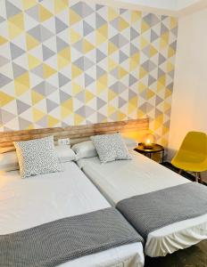 a bedroom with two beds and a yellow wall at Pensión La Florida 19 in Jaén