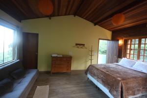a bedroom with a bed and a couch in it at Pousada Campestre Sítio da Lua in Camanducaia