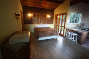 um quarto com uma cama e uma cozinha com um balcão em Pousada Campestre Sítio da Lua em Camanducaia