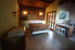 a bedroom with a bed and a kitchen with a counter at Pousada Campestre Sítio da Lua in Camanducaia