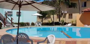 a swimming pool with an umbrella and chairs and a table at Apto 518 - Golden Village Taperapuã in Porto Seguro