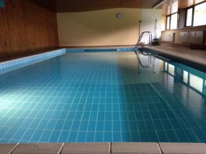 a large swimming pool with blue tiles on the floor at Alpenwohnanlage Lott in Grassau