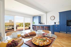 a kitchen with blue cabinets and a table with food on it at Luxury Lodges in Doolin Village with Hot Tubs in Doolin