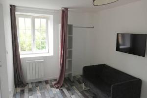 un soggiorno con divano nero e finestra di Maison de bourg avec beaucoup de charme a Nuillé-sur-Vicoin