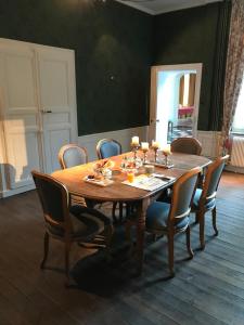 een houten eettafel met stoelen en een houten vloer bij Château d'en haut in Jenlain