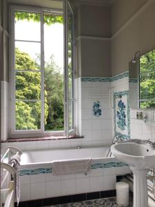 a bathroom with a tub and a sink and a window at Château d'en haut in Jenlain