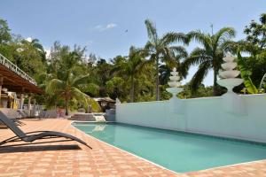 uma piscina num resort com espreguiçadeiras e coqueiros em Chateau Margarita JA em Montego Bay