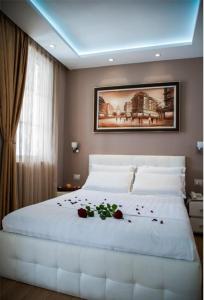 a bedroom with a large white bed with roses on it at Hotel Vila Verde City Center in Tirana