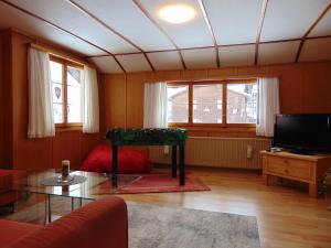 ein Wohnzimmer mit einem Glastisch und einem TV in der Unterkunft Ferienwohnung Casa Plauns-iu in Sedrun