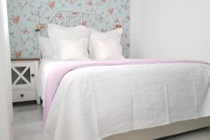 uma cama branca com um cobertor rosa e almofadas brancas em Apartamento Alfarería em Sevilha