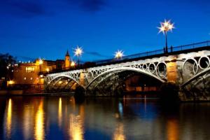 un puente sobre un río por la noche con luces en Apartamento Alfarería en Sevilla