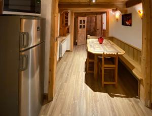 Il comprend une cuisine équipée d'un réfrigérateur en acier inoxydable et d'une table. dans l'établissement Appartement à Courchevel Saint Bon, à Saint-Bon-Tarentaise