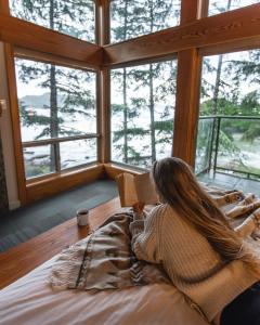 une femme qui se couche sur un lit en lisant un livre dans l'établissement Pacific Sands Beach Resort, à Tofino