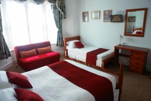 a bedroom with three beds and a chair and a mirror at Filton Guest House in Bristol