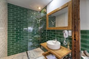 Baño de azulejos verdes con lavabo y espejo en Pivní Hotel en Nepomuk