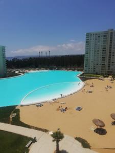 a large swimming pool with a beach and buildings at Departamento Laguna Bahía 808 Velero in Algarrobo