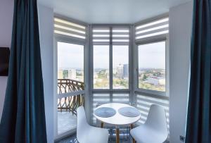 a white table and chairs in a room with windows at Апартаменти "Kopernik" in Kyiv